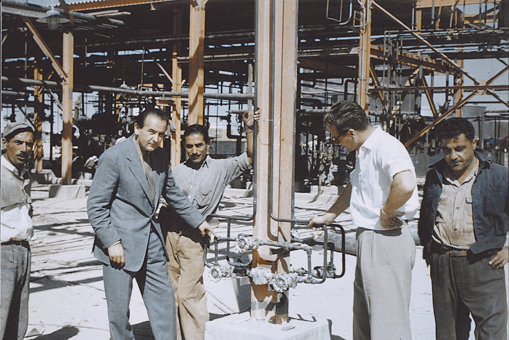 A.K. Velan visiting an oil refinery in the Middle East in 1956. He is pointing out that one Velan Piping King could replace their whole installation.